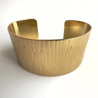 Pulseira em metal dourado texturizada com padrão madeira