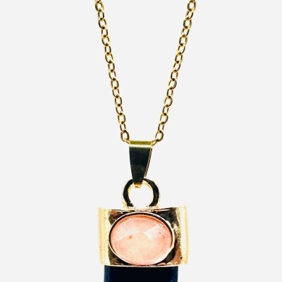 Colar dourado com pendente de dente preto e pedra rosa