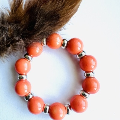 Pulseira com contas laranja e penas castanhas em fundo branco