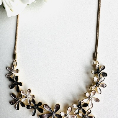 Colar com flores metálicas douradas e prateadas sobre fundo branco