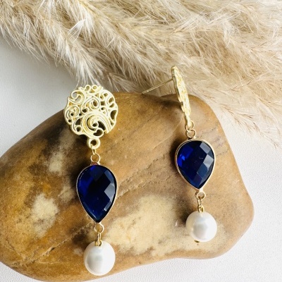 Brincos dourados com pedra azul escura e pérola em pedra marrom clara com penas secas.