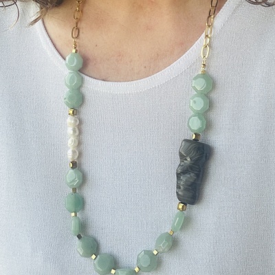 Colar com contas verdes, brancas, douradas e preta usado sobre t-shirt branca