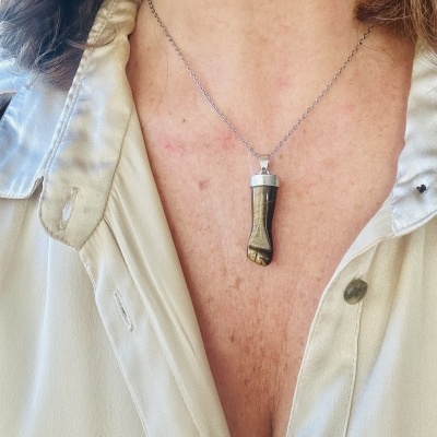 Colar com pendente tipo dente castanho e camisa bege