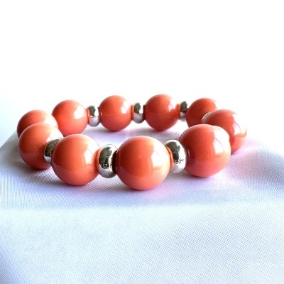 Pulseira de esferas coral com separadores metálicos prateados sobre tecido branco