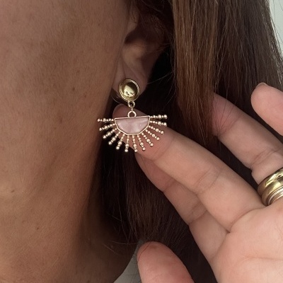 Brinco dourado e rosa pendente em orelha de mulher