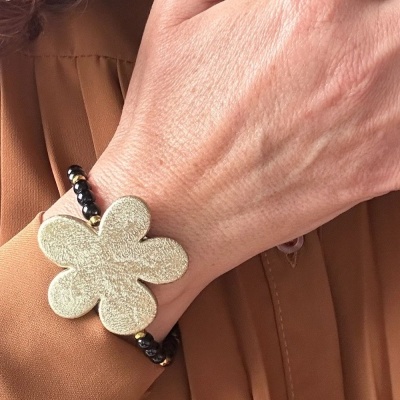 Pulseira com margarida prateada e contas pretas no pulso