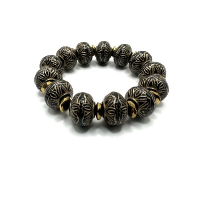 Pulseira elástica com contas pretas e douradas em fundo branco