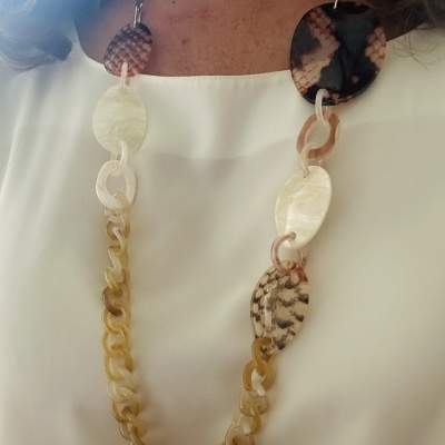 Colar de resina com elos e padrões animal print sobre blusa branca