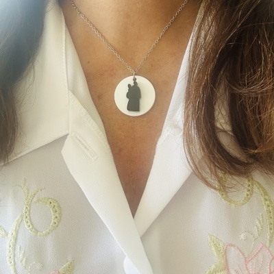 Colar com pendente redondo branco e silhueta de cavalo de xadrez preto, usado com camisa branca bordada