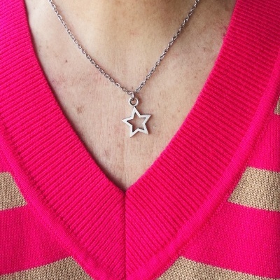 Colar prateado com pendente estrela usado com camisola rosa com riscas bege