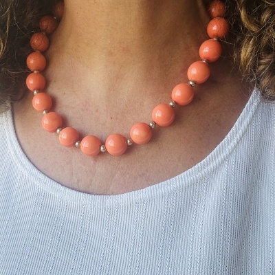 Colar de contas coral com espaçadores dourados sobre blusa branca