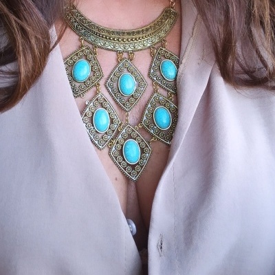 Colar grande dourado com pedras azuis turquesa e blusa bege