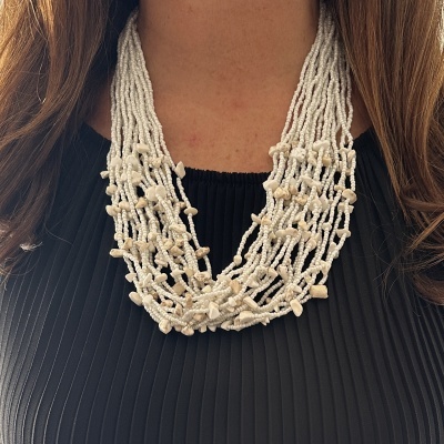 Colar de contas brancas com pedras pequenas, usado por pessoa com blusa preta.