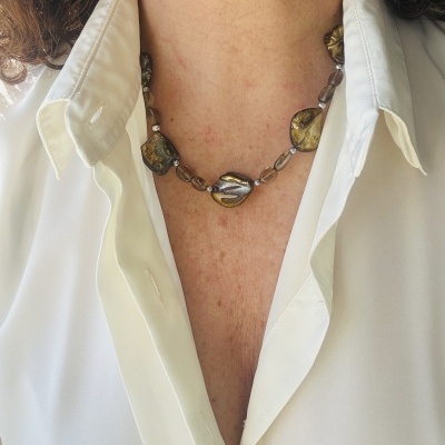 Colar de contas grandes verdes e castanhas com contas pequenas transparentes, usado com blusa branca