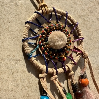 Filtro de sonhos artesanal com fios coloridos, centro em feltro bege, pérolas de madeira e penas cor de rosa