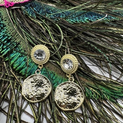 Brincos dourados com pedra transparente sobre penas de pavão coloridas e tecido rosa bordado