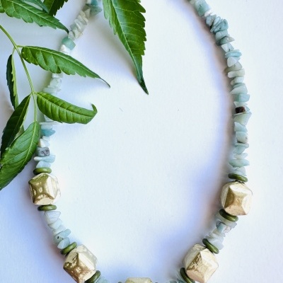 Colar de pedras verdes e contas douradas com folhas verdes