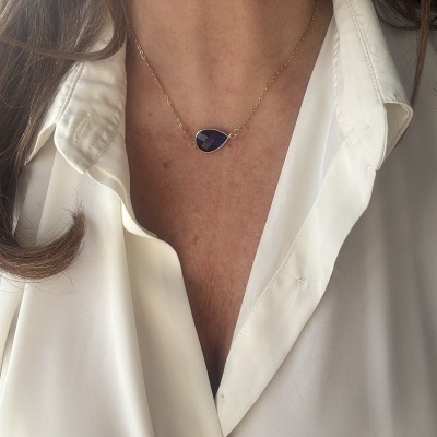 Colar com pendente azul escuro e corrente dourada usado com camisa branca