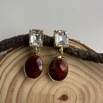 Brincos com pedras transparents e castanhas sobre tronco de madeira