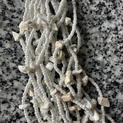 Pulseiras de contas brancas peroladas com pedras brancas sobre granito cinzento