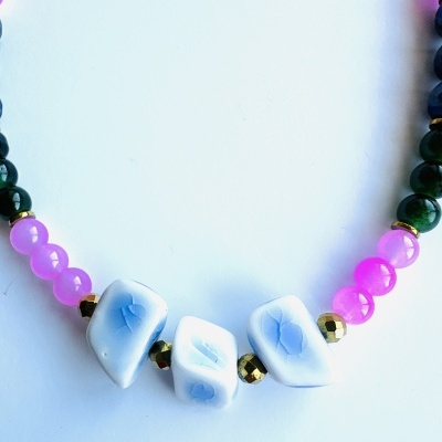 Colar com contas rosas, verdes, douradas e brancas com padrões azuis.