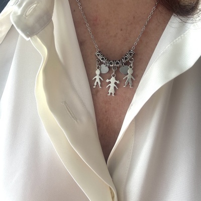 Colar prateado com pingentes de figuras humanas e corações sobre camisa branca