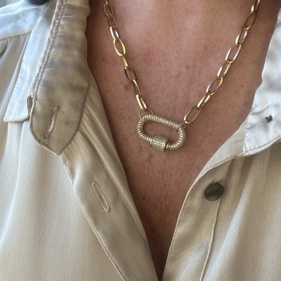 Colar dourado com elos grandes e pendente oval com cristais em camisa bege