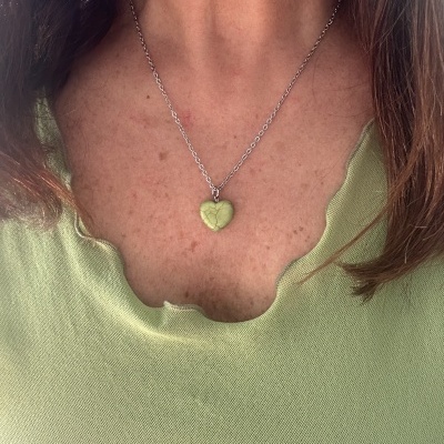 Colar prateado com pendente em forma de coração verde e camiseta verde clara