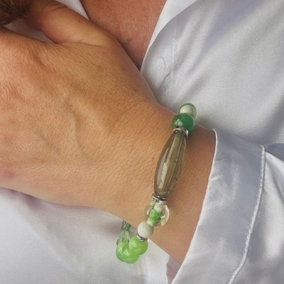 bracelete feminino verde, branco e transparente no pulso de pessoa com camisa branca