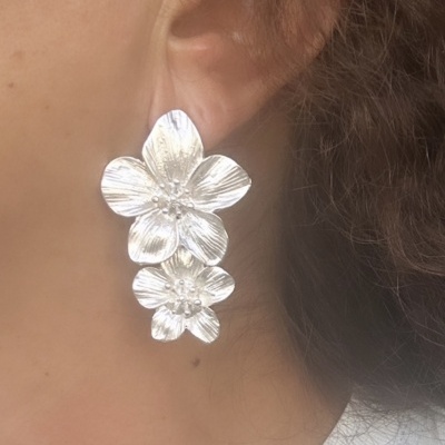 Brinco prateado de flores em orelha