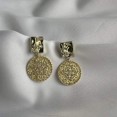 Brincos dourados detalhados sobre tecido branco