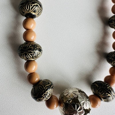 Colar com contas castanho claro, pretas com dourado e uma conta prateada gravada
