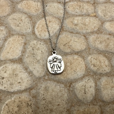 Colar prateado com pingente de anjo sobre superfície de pedras