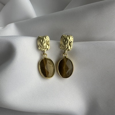 Brincos dourados com pedra castanha em fundo branco