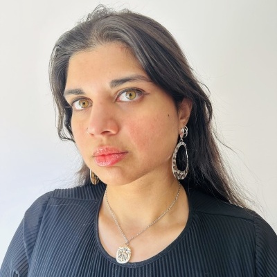 Mulher com brincos e colar prateado e blusa preta canelada