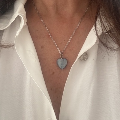 Colar com pendente em forma de coração cinza e corrente prateada em camisa branca