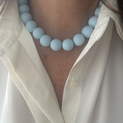 Colar de contas azuis claras com camisa branca.
