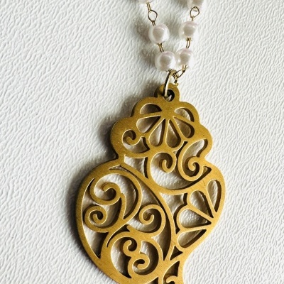 Colar com corrente de pérolas brancas e pendente dourado com padrão recortado