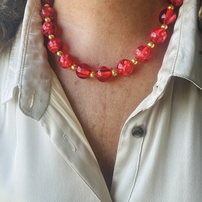 Colar vermelho de contas facetadas com detalhes dourados e camisa branca