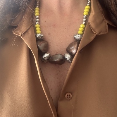 Colar com contas castanhas, prateadas e amarelas usado com camisa castanha