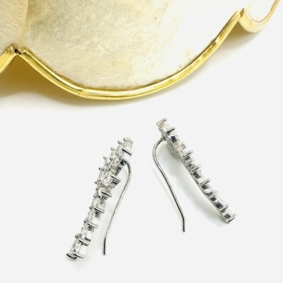 Brincos prateados com pedras claras dispostos em linha