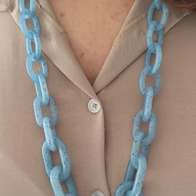 Colar azul claro de elos grandes sobre camisa bege com botões brancos