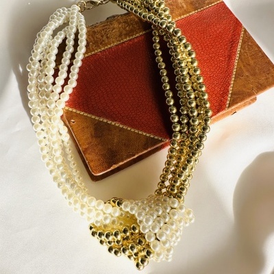 Colar de pérolas brancas e esferas douradas sobre estojo de pele castanha e vermelha