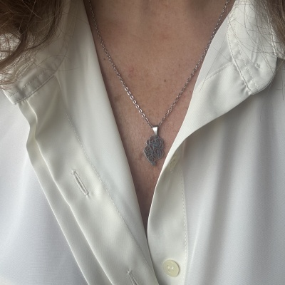 Colar prateado com pendente decorativo em forma irregular em camisa branca