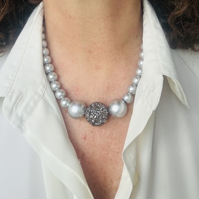 Colar de pérolas prateadas com ornamento central brilhante usado com camisa branca