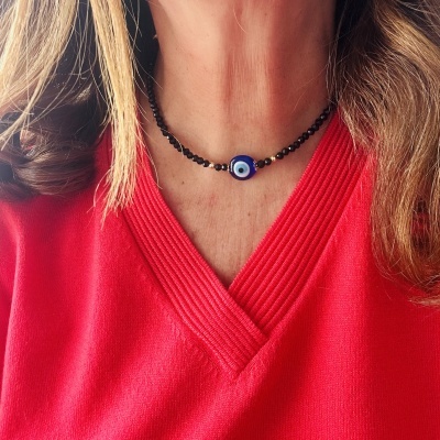 Colar preto com pendente azul de olho turco em pessoa com camisola vermelha