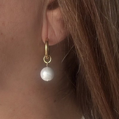 Brinco dourado com pendente perolado na orelha de mulher