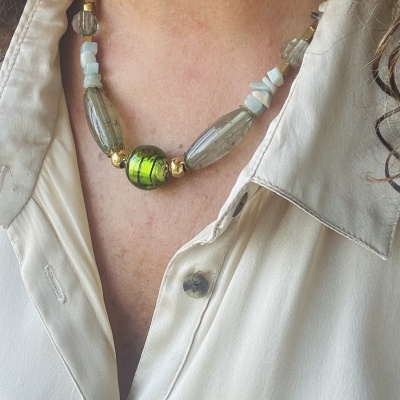 Colar com contas verdes e transparentes usado com camisa bege