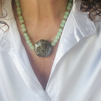Colar de contas verdes com grande pingente oval cinza esverdeado usado com camisa branca