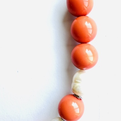 Colar com grandes bolas cor de coral e pérolas brancas num fundo branco